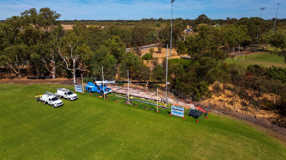 RMF crew and elevated work platform installing a back net at a sports oval